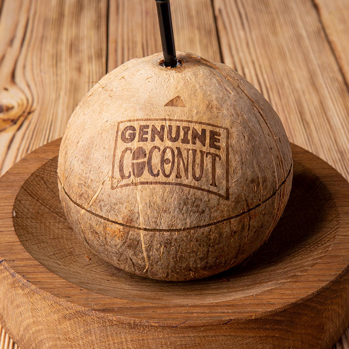 Chilled young green coconut with a straw next to a gym towel and water bottle