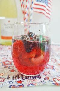 Strawberry and blueberry sangria made with moscato wine on a patriotic tablecloth.