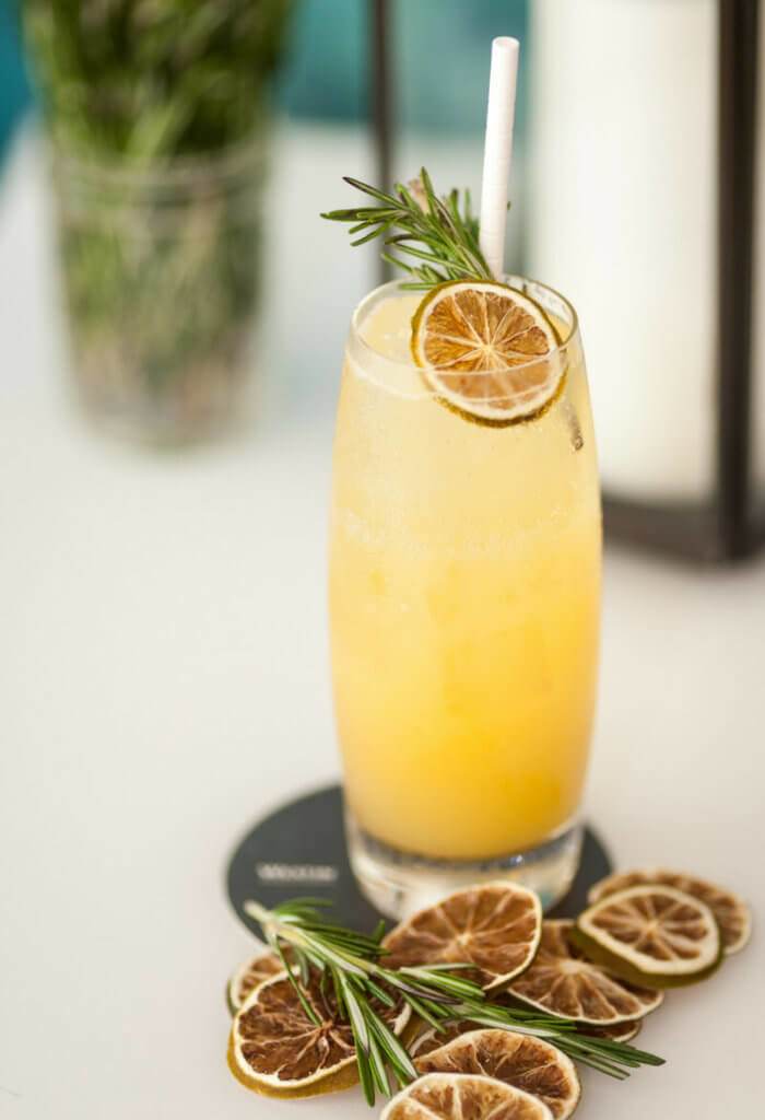 Pineapple lemon cocktail with rosemary garnish.