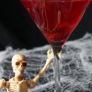 A posable skeleton with the Bowling Green Massacre Martini Halloween drink. It is a twist on the classic cosmopolitan drink made with pomegranate.