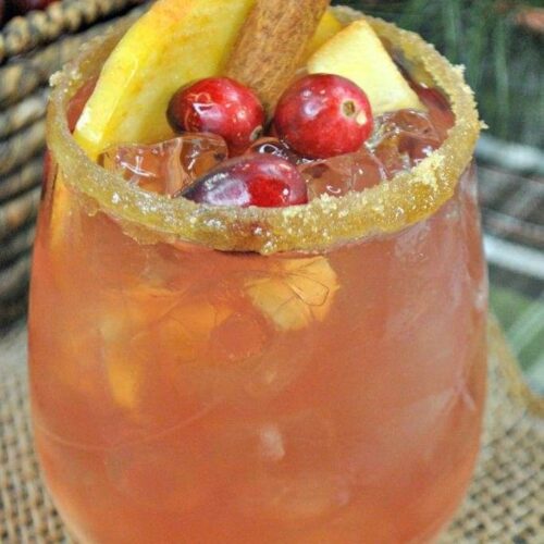 Bourbon cocktail garnished with cranberries and a cinnamon stick.