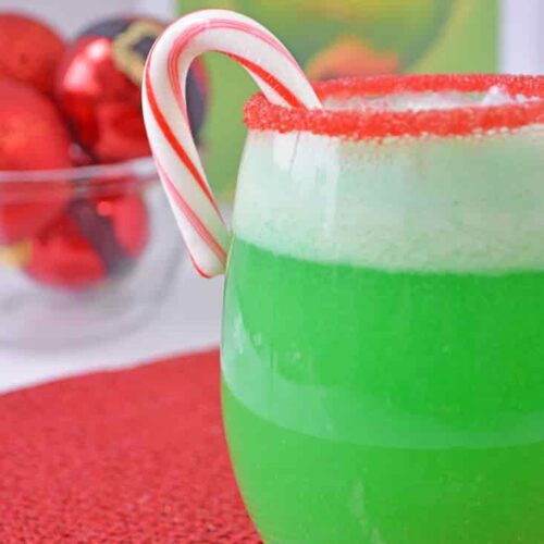 A green ice cream float on a red placemat in front of a dvd of the movie, The Grinch.