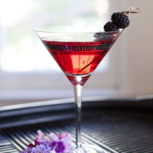 Black Raspberry Martini with Limoncello Cocktail Recipe. Served garnished with fresh blackberries in a martini glass on a bamboo tray.