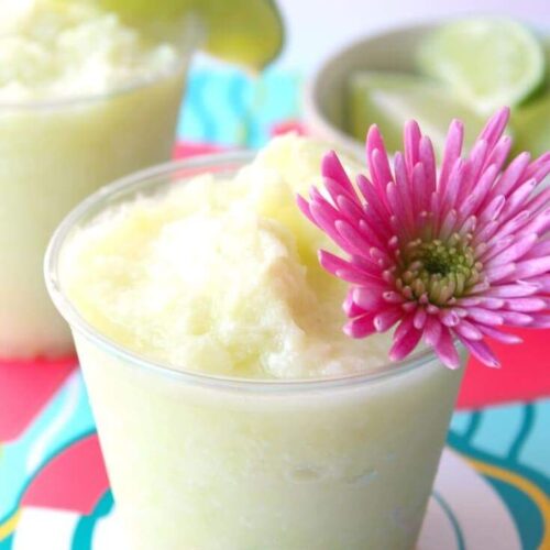 Frozen dole whip cocktail with a pink flower as a garnish.