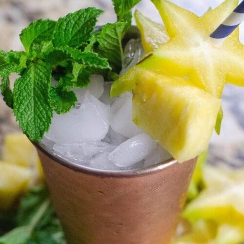 Star Fruit Pineapple Mint Julep on a granite background in a copper julep cup