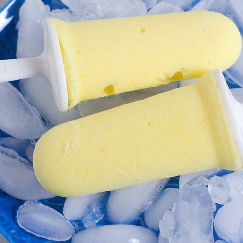 Two Pineapple popsicles on a blue plate of ice.