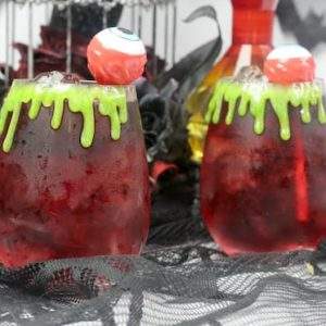 two Halloween cocktails garnished with eyeball cocktail pics