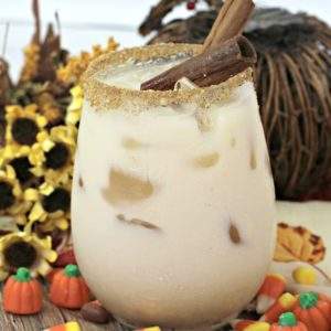 A creamy cocktail served on the rocks on a platter with Halloween candy.