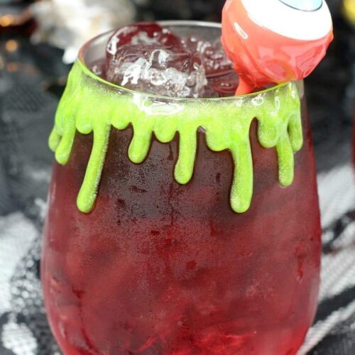 a Halloween drink in a stemless wine glass with an eye ball cocktail pick