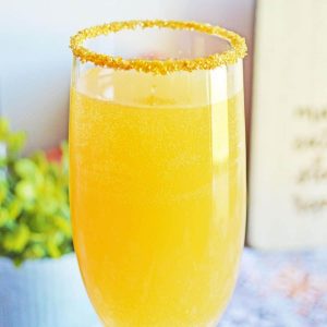 A close up of a champagne flute filled with a mimosa cocktail.