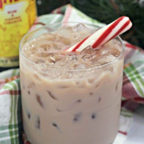 A chocolate peppermint white russian cocktail on a plaid holiday napkin with a bottle of Kahlua.