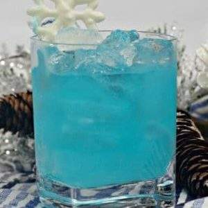 A glass of Elsa's Frozen cocktail, a blue electric long island iced tea on a striped napkin with snowflake decorations.