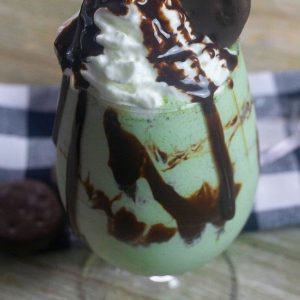 A green chocolate mint milkshake topped with whipped cream and a Thin Mint cookie