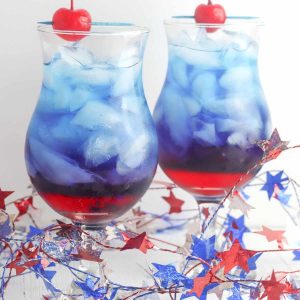 Two red and blue drinks garnished with a maraschino cherry