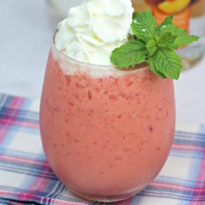 Fresh mint rests atop a dollop of whipped cream on a pink frozen drink.