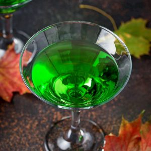a green martini on a dark table with fall leaves