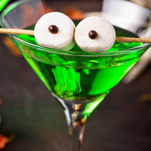 A green martini garnished with an eye ball cocktail garnish.