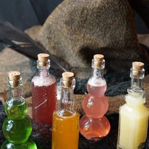 A witch hat with 5 glass bottles filled with colored liquid.