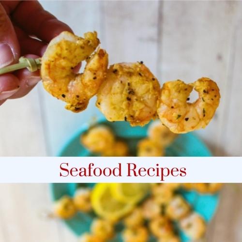 Image of someone holding shrimp on a skewer with text: seafood recipes.