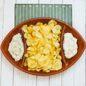 French onion dip and potato chips in a football shaped serving dish.